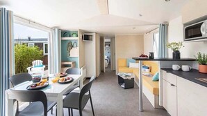 Een compacte, moderne keuken met een eethoek, een klein zitgedeelte en uitzicht op de omgeving.