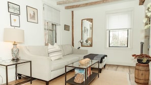 A living room with a sofa, coffee table, and a lamp. There are framed pictures on the wall and a mirror.