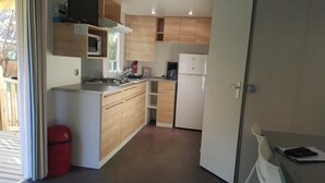 A compact kitchen with wooden cabinets, a gas stove, a microwave, and a refrigerator.