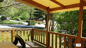 A wooden deck with a yellow canopy, a bicycle, and a house in the background.