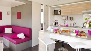 Eine moderne Küche mit Barbereich, einem rosafarbenen Sofa und Frühstücksangeboten auf der Arbeitsfläche.