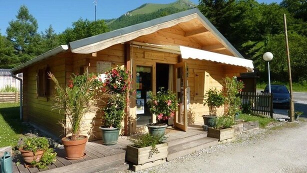 A wooden building with a porch, potted plants, and a sign that reads 'ACCOMMODATION.'