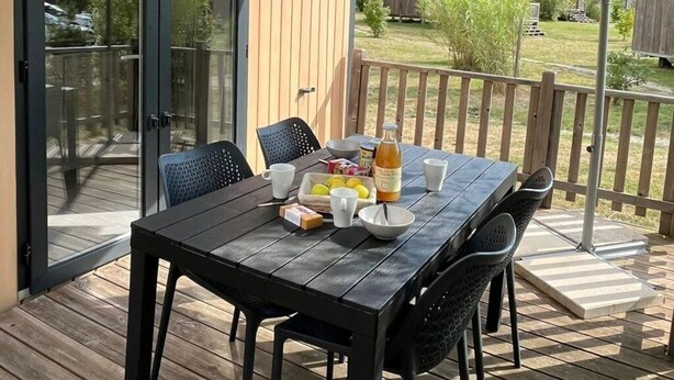 En uteplats med ett bord dukat för frukost, inklusive en flaska, skålar och koppar.