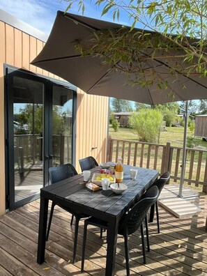 An outdoor patio with a table set for breakfast, including a bottle, bowls, and cups. - ZEcamping 3 étoiles familial piscine couverte locatif LV BBQ 29m2 (Mont-prés-Chambord)