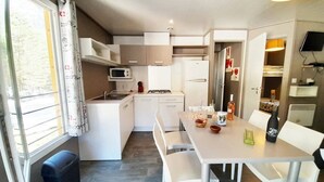 Une cuisine compacte avec des appareils électroménagers blancs, une table à manger avec des chaises et un petit coin salon.