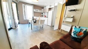 Un appartement moderne comprenant une cuisine, un coin repas et un salon avec un canapé marron et un coussin coloré.