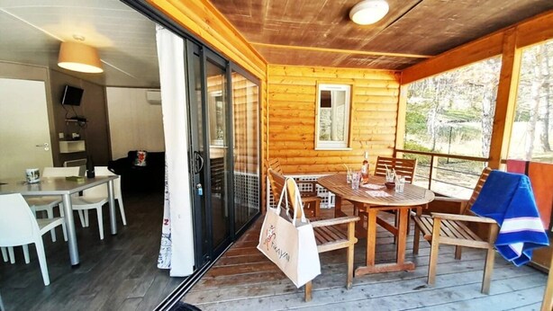 Une cabane en bois comprenant un coin repas, un téléviseur fixé au mur et une vue sur l’extérieur.