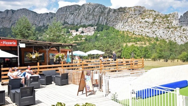 Restaurante com área externa e vista para uma paisagem montanhosa.