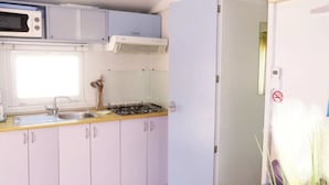 Une cuisine équipée d’un four à micro-ondes, d’une cuisinière, d’un évier et de placards.