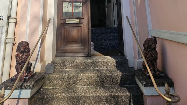 Una entrada de edificio con puerta de madera, escalera y estatua de león.
