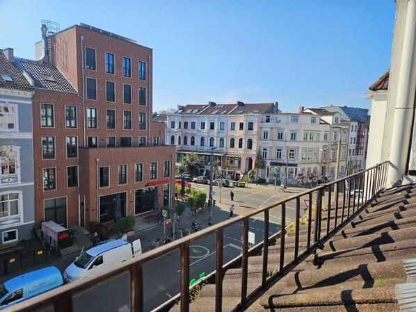 Ein mehrstöckiges Gebäude mit Backsteinfassade und großen Fenstern, gelegen in einer Stadtstraße inmitten anderer historischer Bauten.