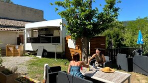 A patio area with outdoor seating, a white RV, and a tree.