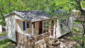 A small, single-story cabin with a porch and a covered outdoor seating area.