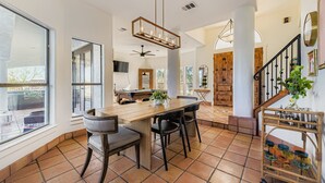 Una cocina amplia con una isla grande, iluminación colgante moderna y vistas al patio exterior.