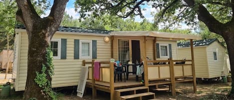 A mobile home with a porch, a table with chairs, and a small deck.