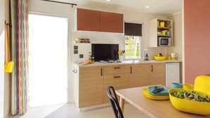 Una cocina moderna con armarios de madera, una estufa a gas y un microondas. Hay una mesa de comedor con platos amarillos y un bol de ensalada.