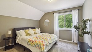 A bedroom with a bed, a bedside table, a lamp, a window with curtains, and a plant. - Basketball Court, Pickleball, Karaoke, 6 Beds (Minneapolis)