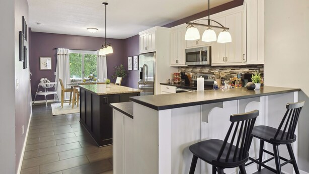 A modern kitchen with white cabinets, a central island with bar stools, stainless steel appliances, and pendant lighting. - Basketball Court, Pickleball, Karaoke, 6 Beds (Minneapolis)