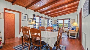 A dining room with a wooden ceiling, white walls, and a table set for four.