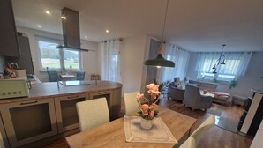 A modern kitchen with a central island, dining area with a wooden table and chairs, and a living room with a sofa and a coffee table.