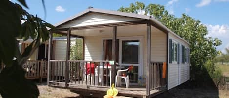 A mobile home with a covered porch, a small deck, and a visible window.