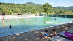 A swimming pool with people in the water and on the beach.