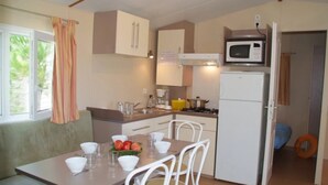 A compact kitchen with white cabinets, a microwave, a refrigerator, and a dining table with chairs.
