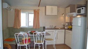 A compact kitchen with a dining area, including a table, chairs, and a sofa.