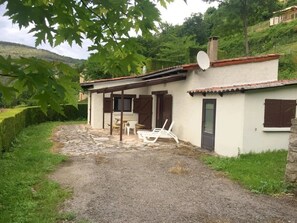 A rustic house with a patio, a table, and two chairs.