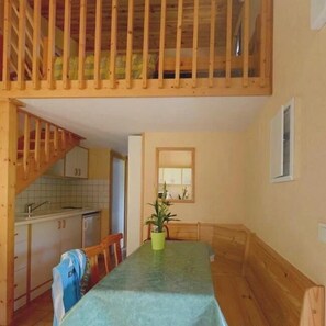Une cuisine de taille réduite, dotée de meubles en bois, d’une table à manger et d’un escalier menant à un niveau supérieur.