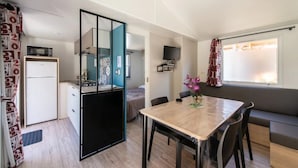 Un espacio habitable compacto con kitchenette, comedor y zona de estar.