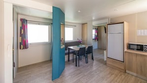 Un espacio habitable compacto con kitchenette, comedor y baño pequeño.