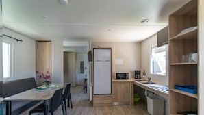 Una cocina compacta con comedor, microondas, cafetera y refrigerador.