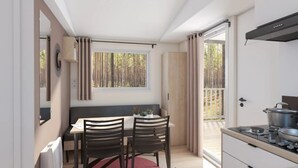 A compact kitchen with a dining area, a window with curtains, and a view of the outdoors. - ZEcamping 4* familial piscine locatif TV clim 27m2 4 pers (Saint-Rome-de-Tarn)