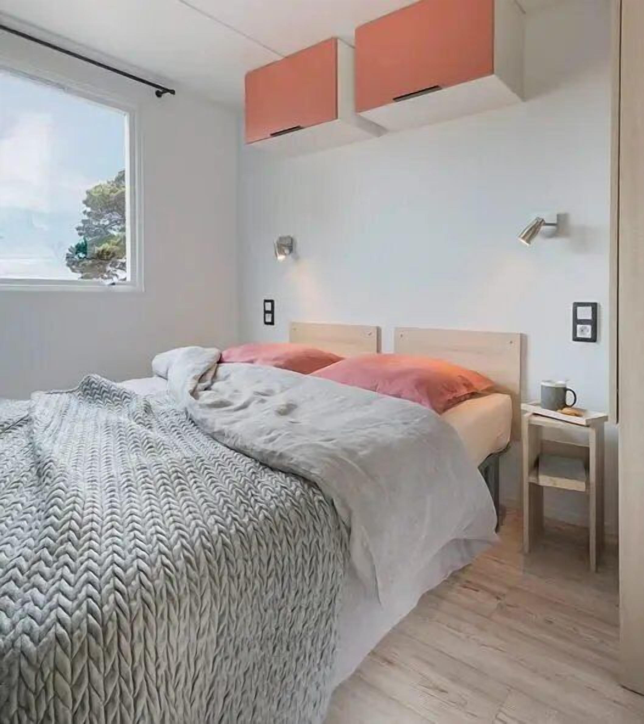 A modern bedroom with a bed, a nightstand, a window, and a view of the outdoors.