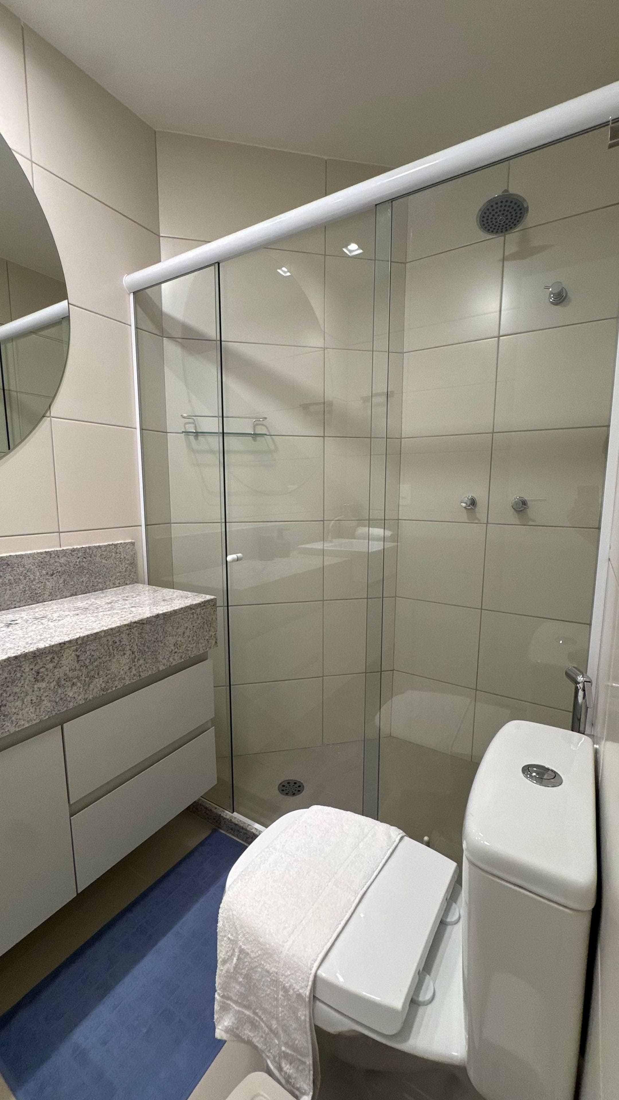 Un baño moderno con ducha envuelta en vidrio, encimera de granito y váter blanco.