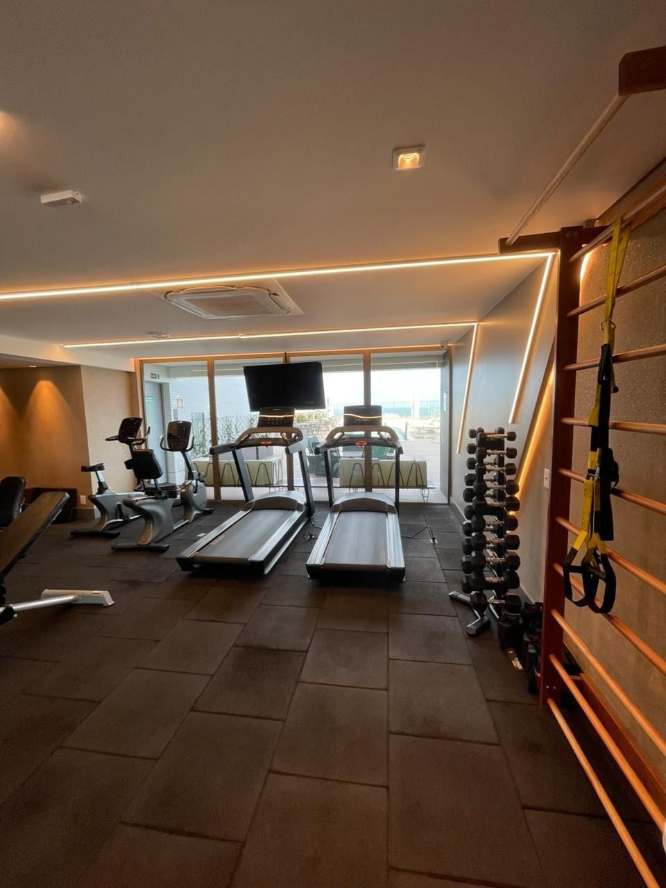 A gym with treadmills, elliptical machines, and a weight rack.
