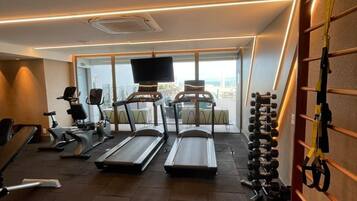 A gym with treadmills, elliptical machines, and a weight rack.