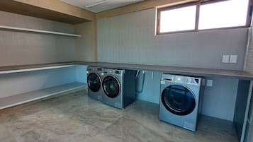 Un cuarto de lavandería con dos lavadoras de carga frontal, una encimera y una ventana.