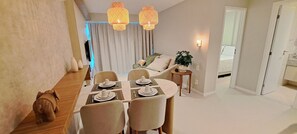 A dining area with a table set for four, a sofa, and a small side table with a plant. - Flats no Parque do Cais Recife  (Recife)