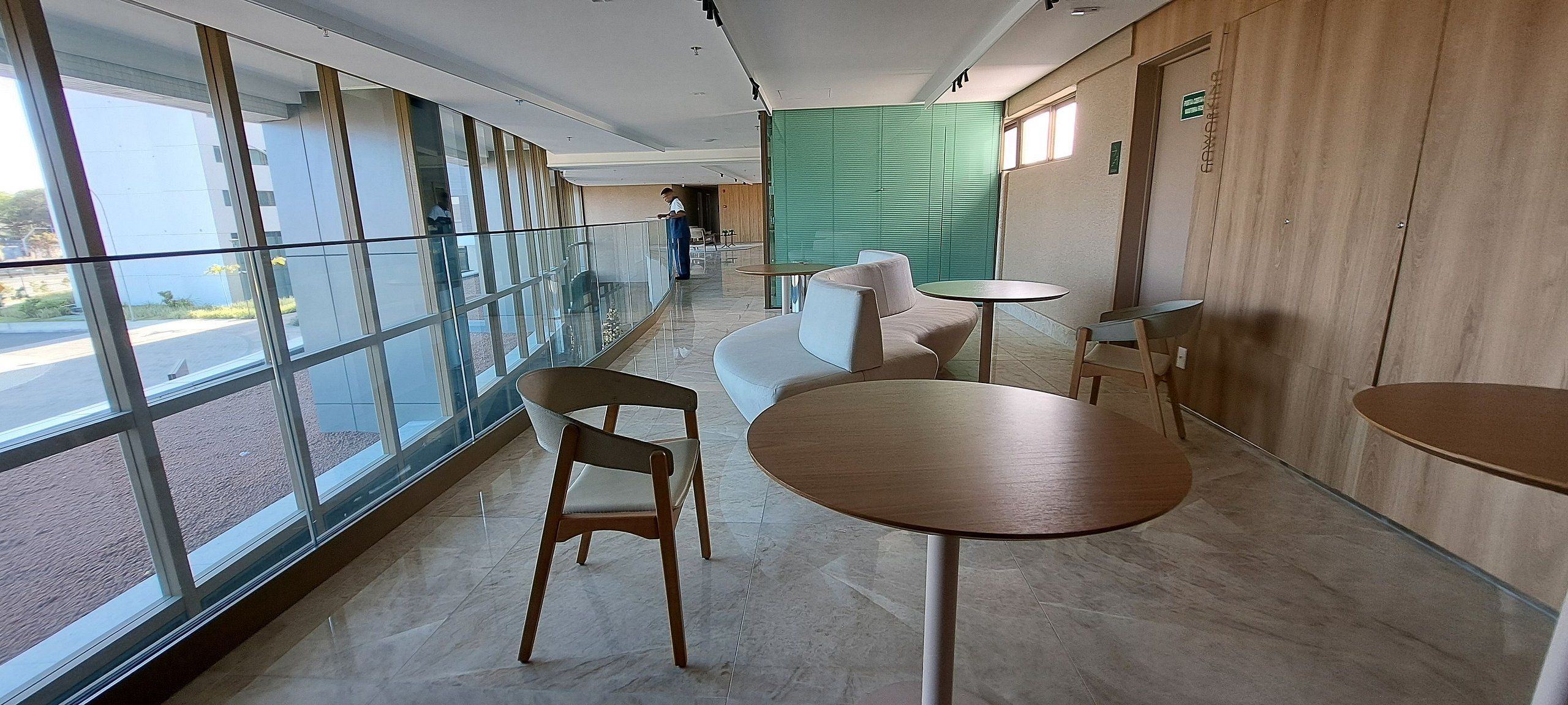 Een modern interieur met grote ramen, een zithoek met tafels, en een groene scheidingswand.