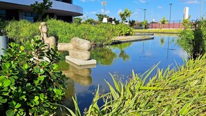 A serene outdoor area with a reflective water feature, stone sculptures, and lush greenery. - Flats no Parque do Cais Recife  (Recife)