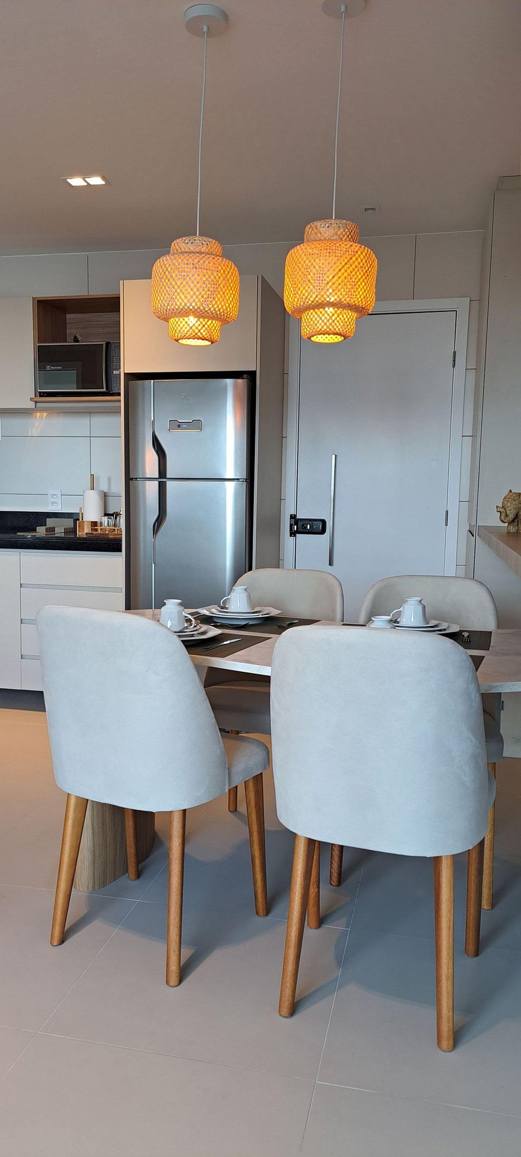 Una cocina moderna con un refrigerador de acero inoxidable, armarios blancos y una mesa de comedor con cuatro sillas.