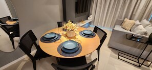 A dining area with a round table set for four, surrounded by black chairs. - Flats no Parque do Cais Recife  (Recife)