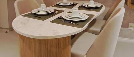 A dining area with a round table, chairs, and a pendant light fixture.