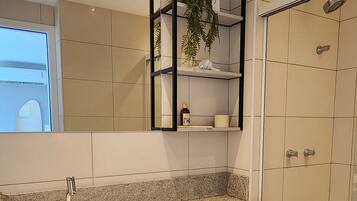 Un baño moderno con un lavabo blanco, un espejo y una ducha.