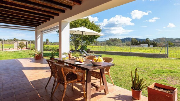 An outdoor patio with a wooden table, wicker chairs, and a white umbrella. - New! Villa Cana Vane (Ibiza)