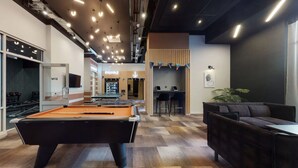 Ein moderner Aufenthaltsraum mit Billardtisch, Bar und einer Sitzecke mit Sofa und Sesseln.