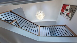 Un interno moderno con una scala, un lampadario e un'opera d'arte astratta.
