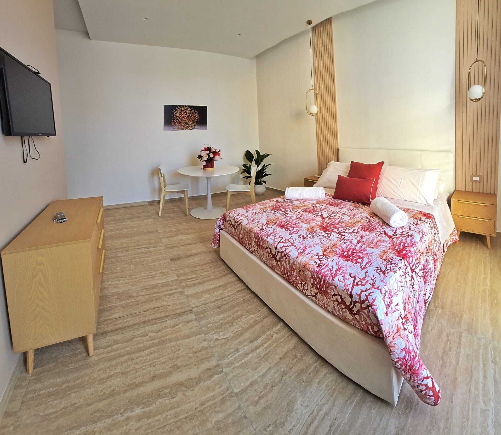 A modern bedroom with a large bed, bedside tables, a desk, and a chair.